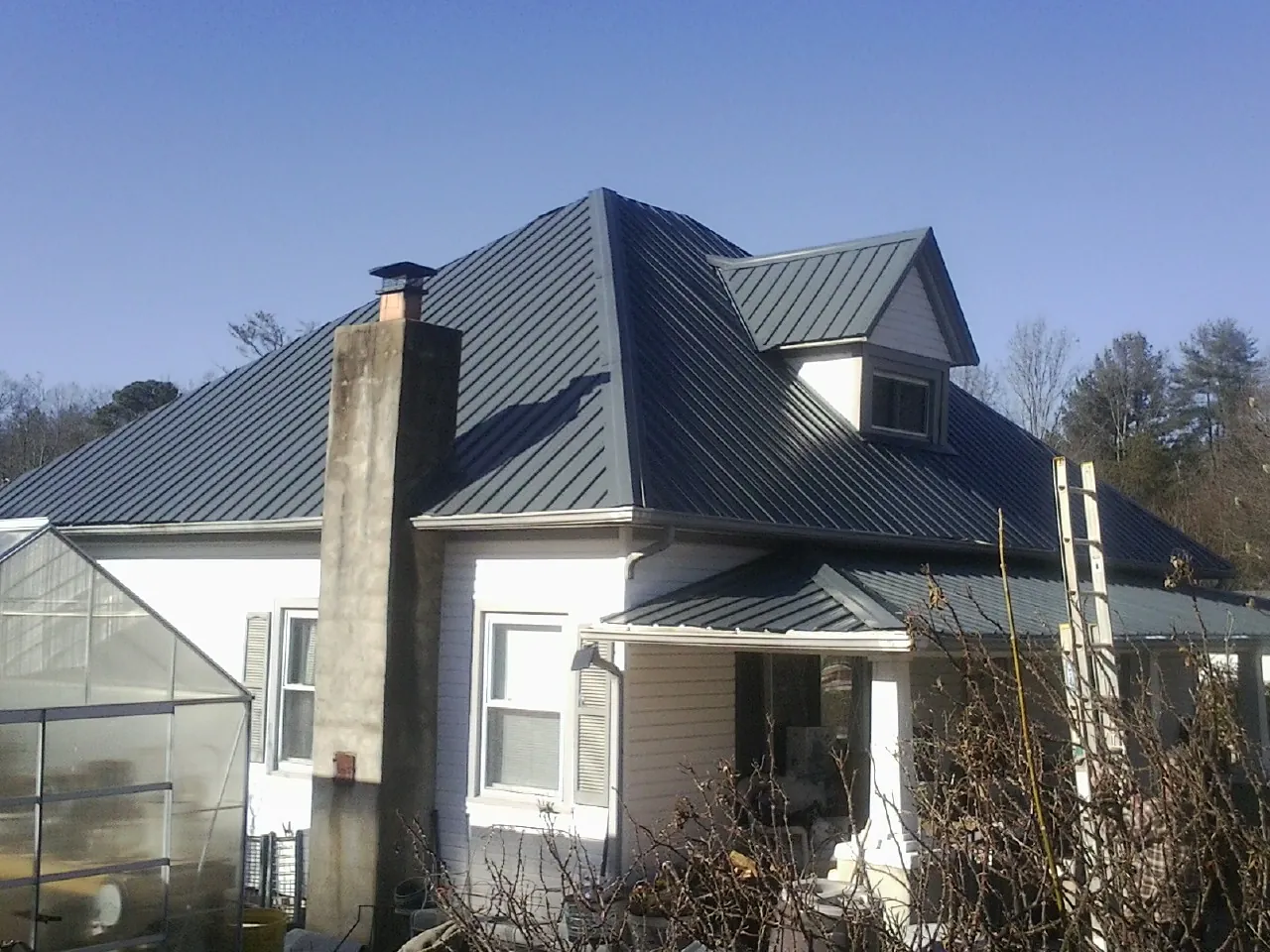 Dark blue standing seam metal roof on a white farmhouse with dormer — Slate & Tile Roof Repair by Roofing Brothers in Pollock Pines