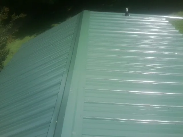 New green metal panels meeting at the ridge of a roof — Flat Roof Repair work by our crew in Pollock Pines