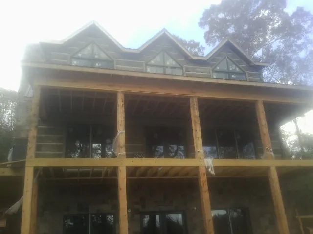 Dormers and porch framing on a large log home under construction — Roof Coating work by our crew in Pollock Pines