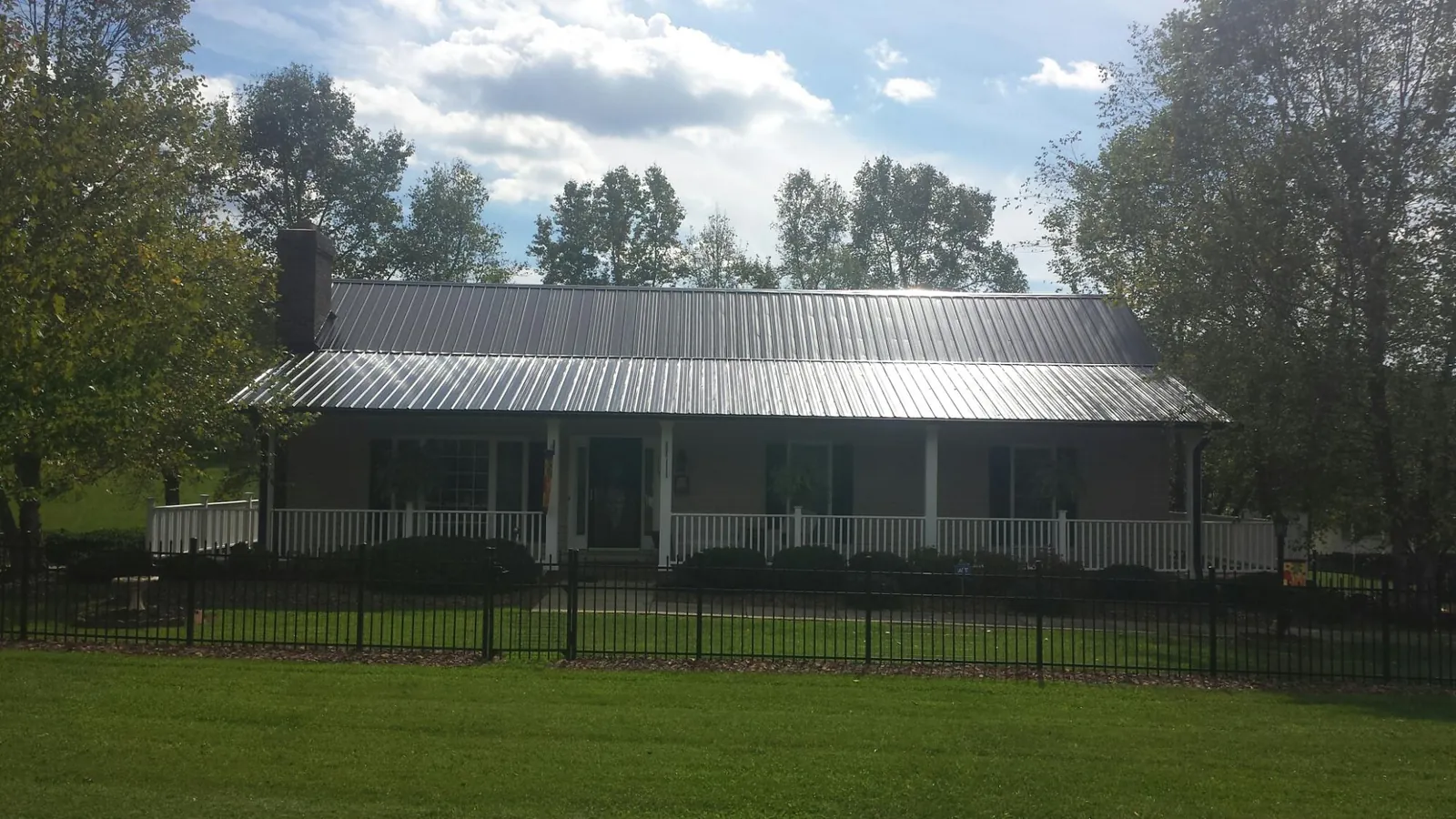 Gray metal roof on a brick ranch with a full width front porch — Gutter Guard Installation work by our crew in Pollock Pines