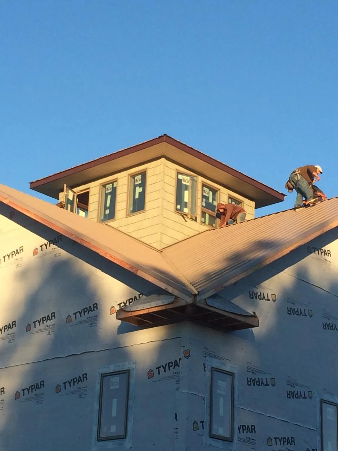 Roofers working around a rooftop cupola on a new metal roof at sunset — Roof Waterproofing in Pollock Pines by Roofing Brothers